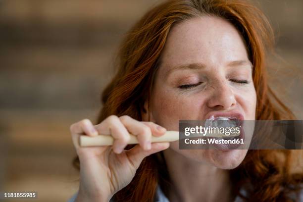 portrait of redheaded woman brushing teeth - zahnpflege stock-fotos und bilder