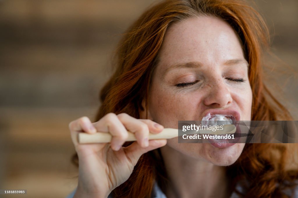 Portrait of redheaded woman brushing teeth