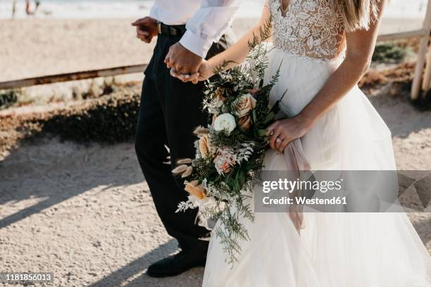 close-up of bride and groom walking on path at the coast - wedding dress photos et images de collection