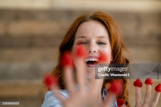 portrait of laughing redheaded woman with raspberries on her fingertips - superfood stock-fotos und bilder