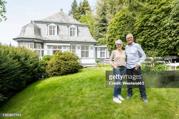 smiling senior couple standing in garden of their home - best ager paar garten stock-fotos und bilder