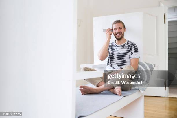 smiling young man using smartphone at home - answering machine stock pictures, royalty-free photos & images