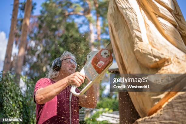 wood carver carving sculpture, using chainsaw - sculpteur photos et images de collection