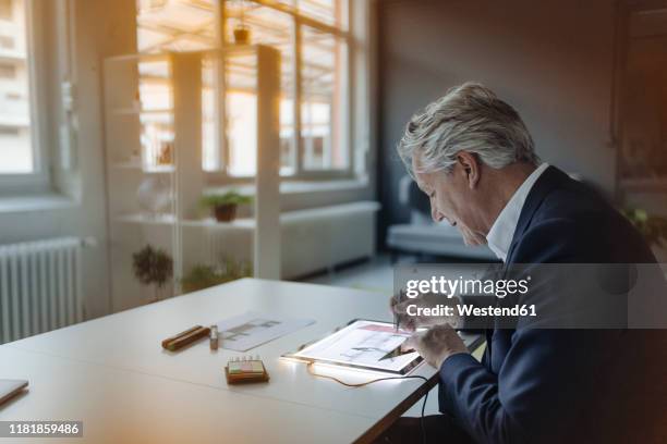 senior businessman drawing on shining tablet - person in suit construction stock-fotos und bilder