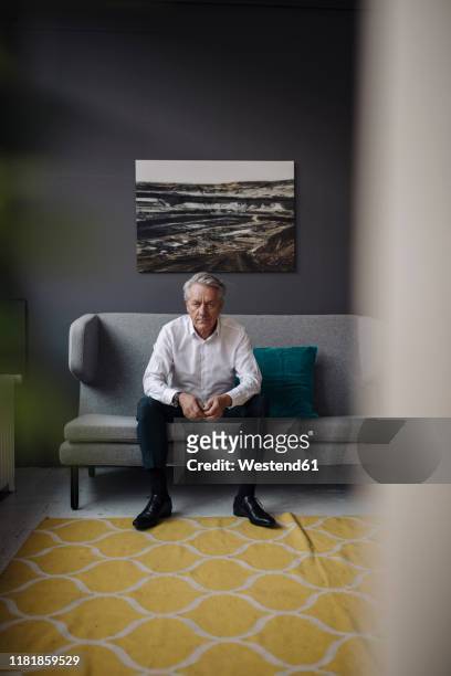 portrait of senior businessman sitting on a couch - sitting on couch imagens e fotografias de stock