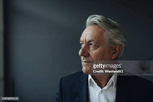 portrait of a senior businessman looking away - grauer anzug stock-fotos und bilder