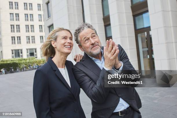happy businessman and businesswoman in the city looking up - pleading stock pictures, royalty-free photos & images