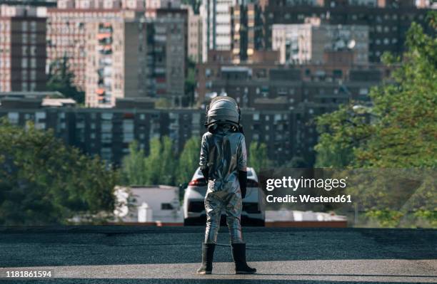 rear view of boy dressed as an astronaut standing on a street in the city - retro futurism space stock pictures, royalty-free photos & images
