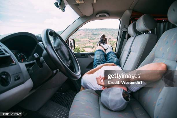 young man with leg prosthesis resting in camper van - man sleeping with cap stock pictures, royalty-free photos & images