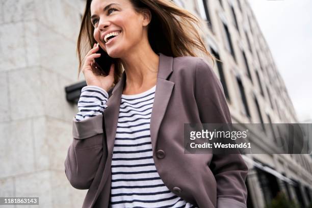 happy businesswoman on the phone in the city - gestreept jak stockfoto's en -beelden