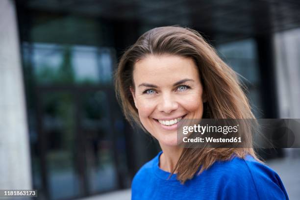 portrait of attractive brunette woman wearing blue top in the city - hair brunette imagens e fotografias de stock