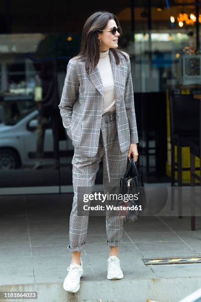 smiling stylish woman standing outside a restaurant looking around - checked blazer stock pictures, royalty-free photos & images