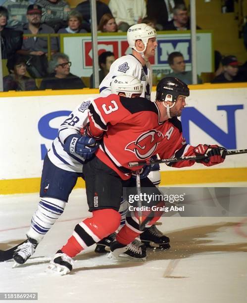 Ken Danyko of the New Jersey Devils skates against Tie Domi and Kirk Muller of the Toronto Maple Leafs during NHL game action on December 10, 1996 at...