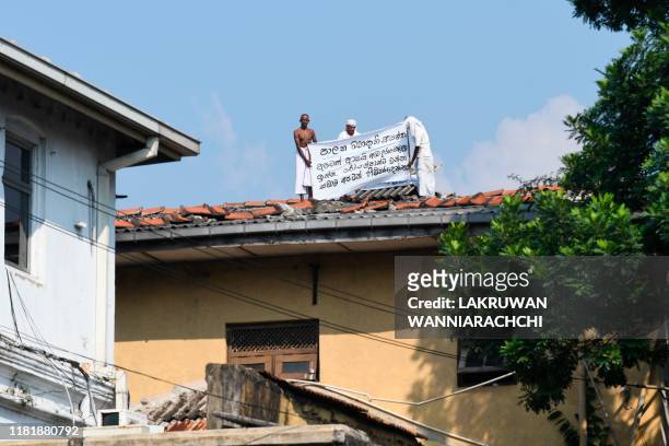 Prisoners display a banner on the roof of a building inside the Welikada prison in Colombo on November 12 to protest the pardon for man who murdered...