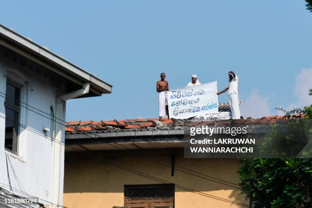 Prisoners display a banner on the roof of a building inside the Welikada prison in Colombo on November 12 to protest the pardon for man who murdered...