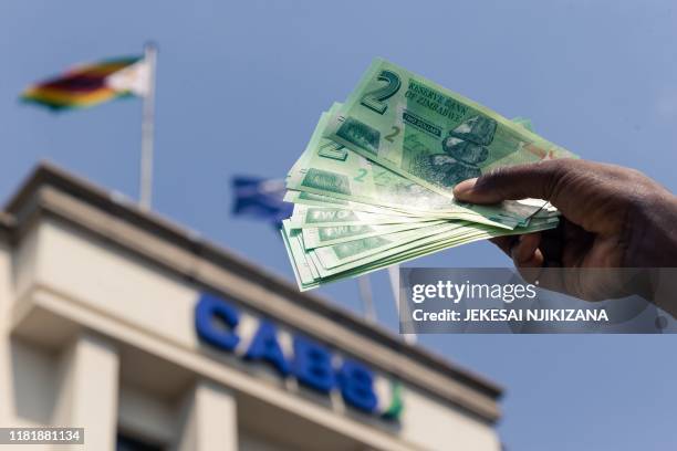 Man shows a wad of the new Zimbabwe two-dollar notes he received from a bank in Harare on November 12, 2019.