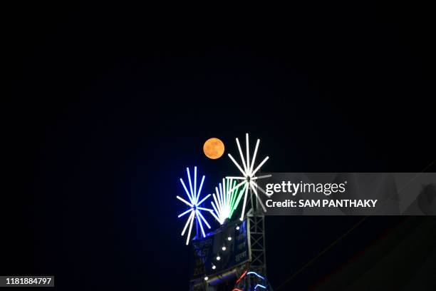 The full moon is seen above illuminated decorations marking Hindu, Sikh and Jain festival called 'Kartik Purnima' or full moon day, at Siddhpur, some...