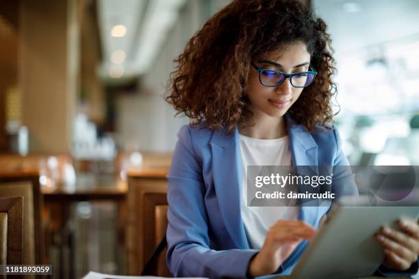 businesswoman using digital tablet at a cafe - choosing insurance stock pictures, royalty-free photos & images