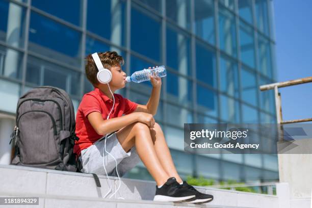 boy with headphones drinking water - cold drink hot day stock pictures, royalty-free photos & images
