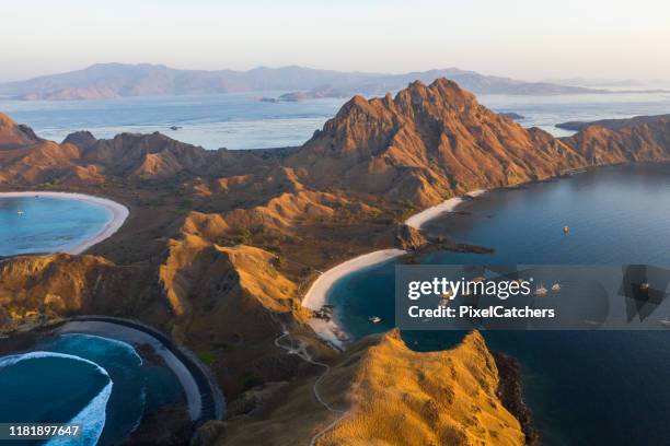 isla padar al atardecer con barcos anclados en la bahía - east nusa tenggara fotografías e imágenes de stock