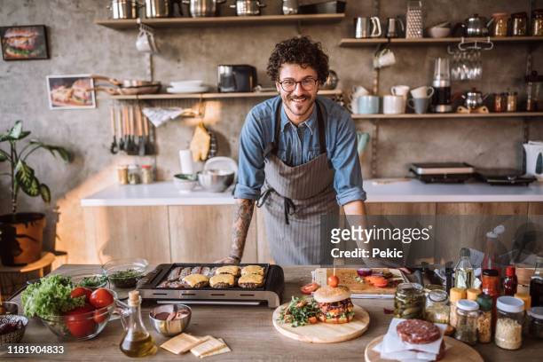 er ist in seinem element beim kochen - american burger stock-fotos und bilder