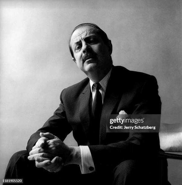 Portrait of American theatrical producer David Merrick as he sits, with clasped hands, in front of a gray background, New York, New York, July 21,...