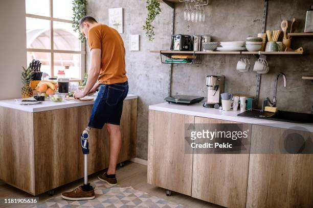 man with amputee leg making breakfast at home - amputee home stock pictures, royalty-free photos & images