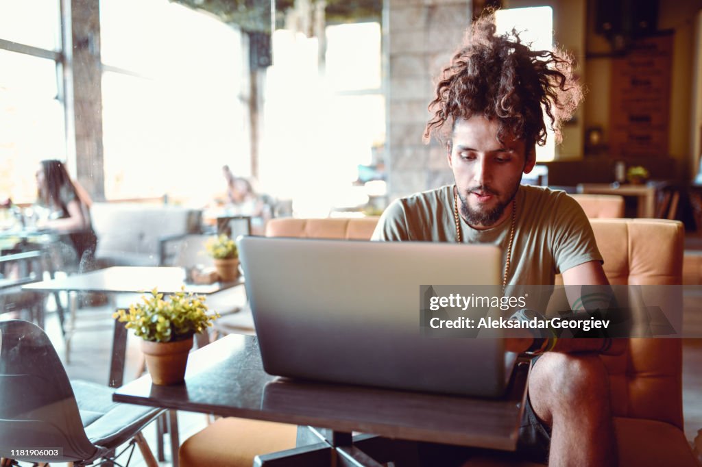 Young Hipster Male Relaxing With Laptop In Coffee Bar