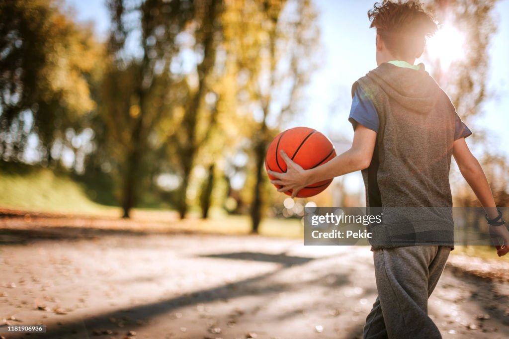 Rear view of boy with basketball ball on sunny day