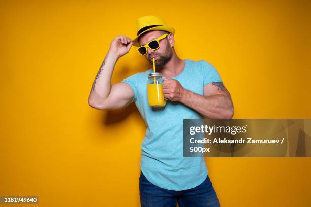 man posing with bright orange drink - man muscles cocktail stock pictures, royalty-free photos & images