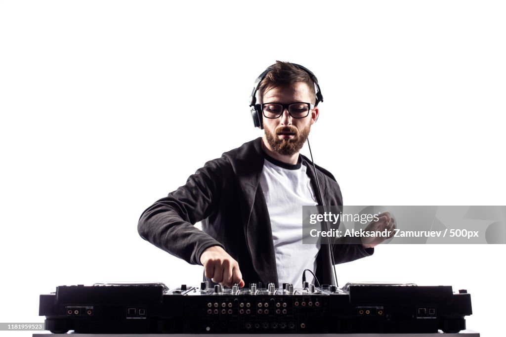 Trendy Male Dj Posing Against Mixing Console