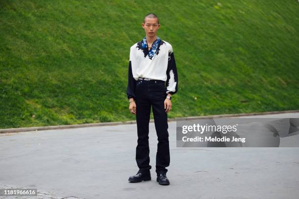 Model Xu Meen wears a chain necklace, whte and black splattered paint cowboy style shirt, blue collar, black pants, and black shoes after the Kenzo...