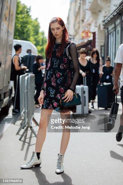 Model Remington Williams wears a sleeveless black floral dress, fishnet top, green Coach bag, and white boots after the Paul Smith show during Paris...