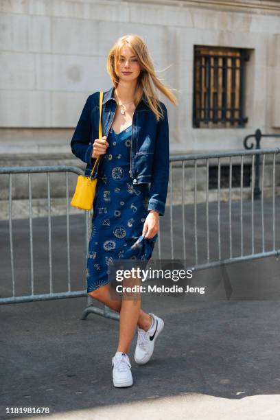 Model Lauren de Graaf wears a denim jacket, blue slip astrology dress, yellow purse, and white Nike sneakers after the Chanel show during Couture...