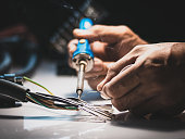 Electricians are using a soldering iron to connect the wires to the metal pin.