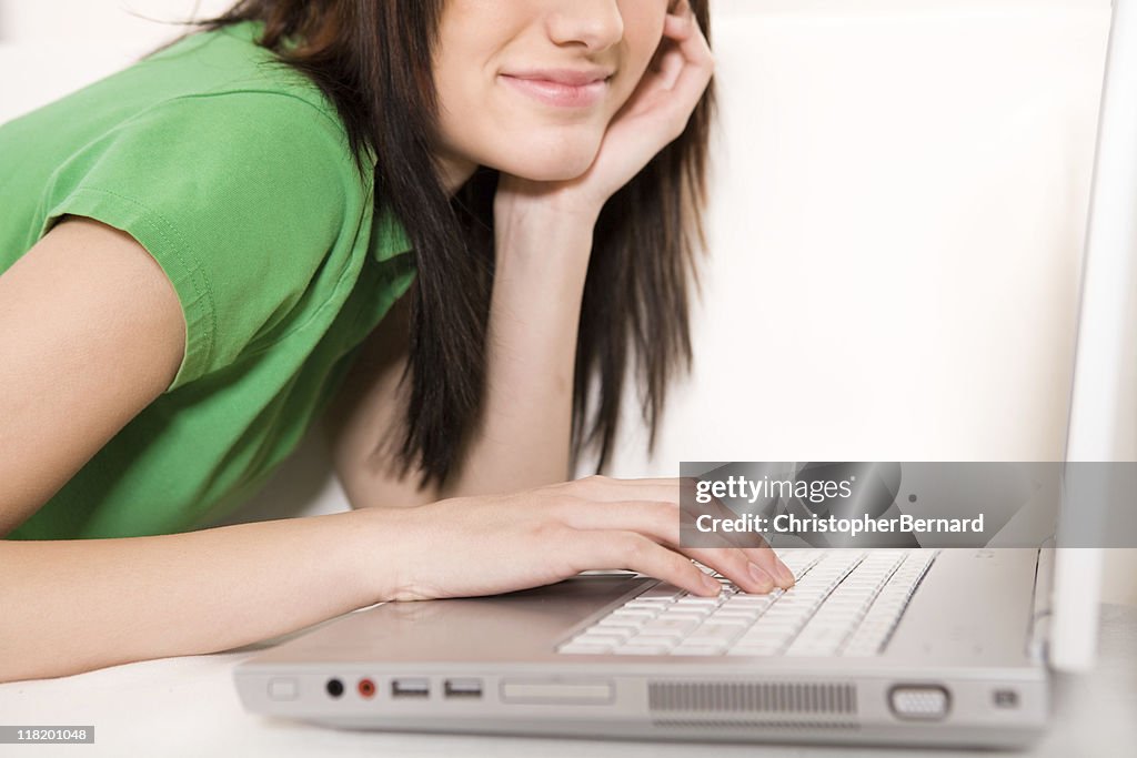 Adolescente sonriente usando computadora portátil