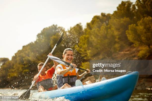 pareja alegre disfrutando del kayak - kayak fotografías e imágenes de stock