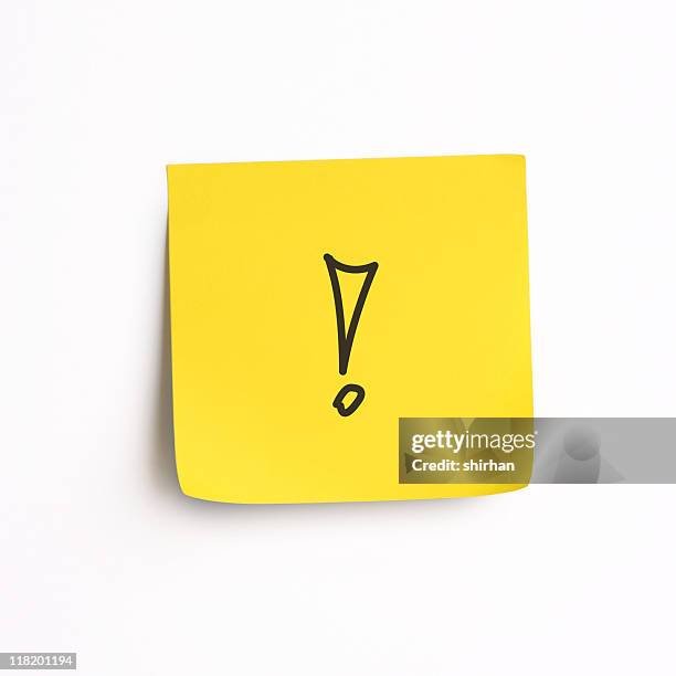 single stick-on yellow note with an exclamation mark - punctuation mark stockfoto's en -beelden