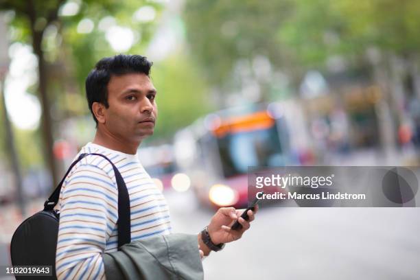 hombre esperando en una parada de autobús - expatriado fotografías e imágenes de stock
