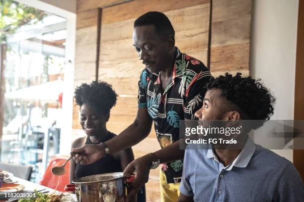 father serving food to his daughter and son - black family reunion stock pictures, royalty-free photos & images