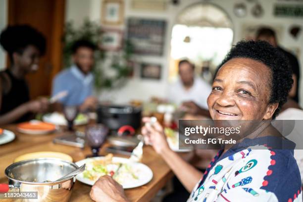 portret van senior vrouw eten en kijken naar camera - pardo stockfoto's en -beelden