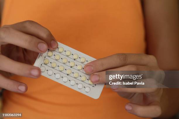 woman's hands holding birth control pills - anticonceptivo fotografías e imágenes de stock