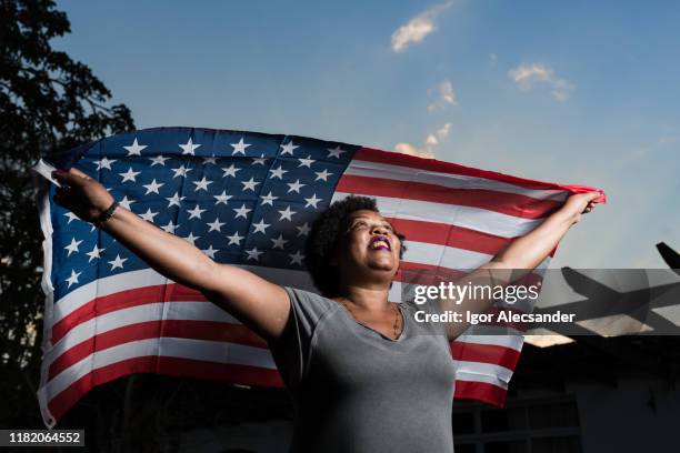 proud woman raising the flag of the united states of america - immigration ceremony stock pictures, royalty-free photos & images