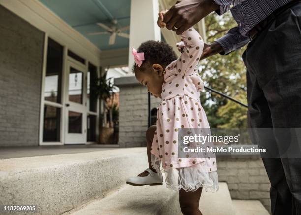 father and daughter (18 months) walking up steps to house - ballade famille photos et images de collection