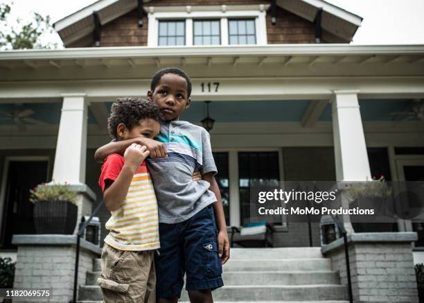 two boys (3 yrs and 6 yrs) playing in front of house - brothers boys cuddle stock pictures, royalty-free photos & images