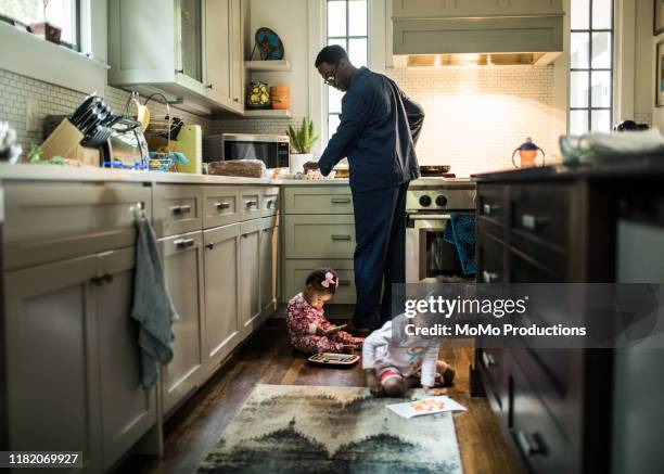 father cooking breakfast for daughters in kitchen - family breakfast stockfoto's en -beelden