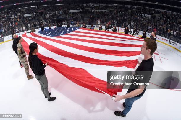 Army members and fans hold an American flag on the ice during the National Anthem prior to the first period against the Minnesota Wild on Salute to...