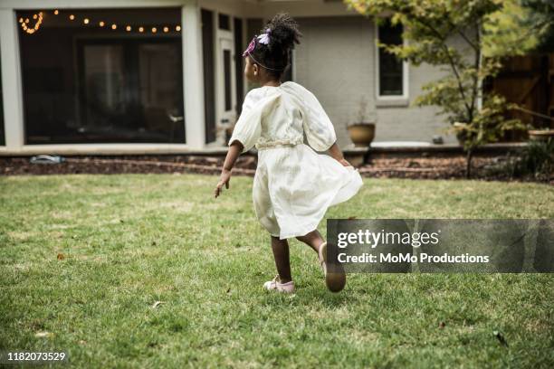 young girl (3 yrs) playing in backyard - white dress back stock pictures, royalty-free photos & images