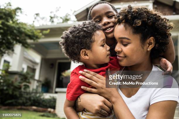 single mother playing with young sons in front of house - ethnische zugehörigkeit stock-fotos und bilder