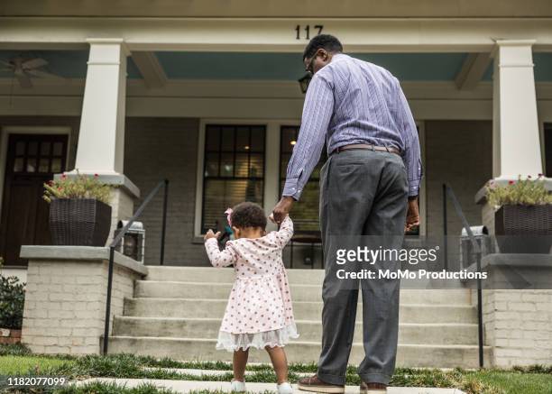 father and daughter (18 months) walking up steps to house - african american girl wearing a white shirt stock pictures, royalty-free photos & images
